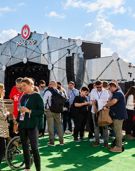 Participantes em networking ao ar livre, junto a um palco e palmeiras